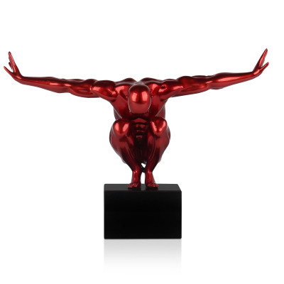Statua di colore rosso metallizzato che si chiama Equilibrio piccolo e che rappresenta una figura umana maschile accovacciata su un piedistallo