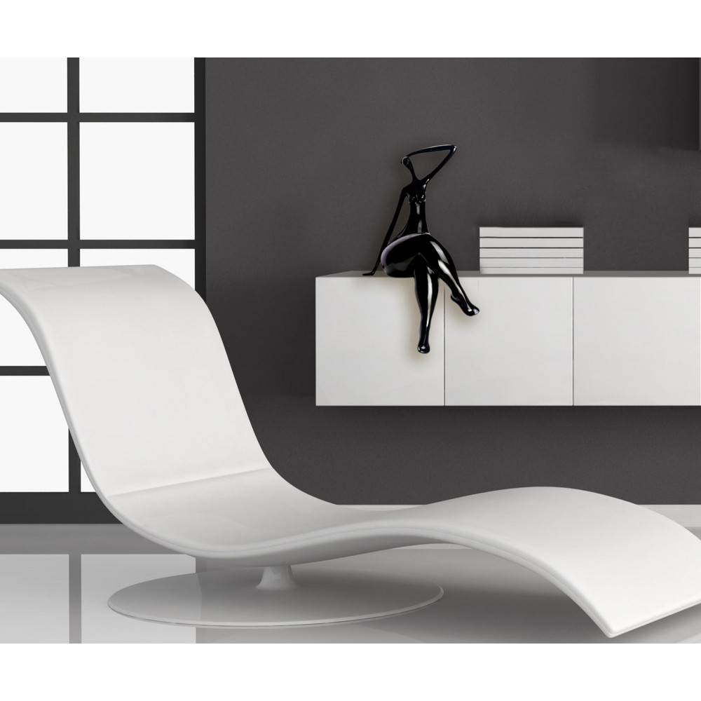ambiente living con chaise longue, mobile a parete bianco e statuetta nera raffigurante una donna seduta