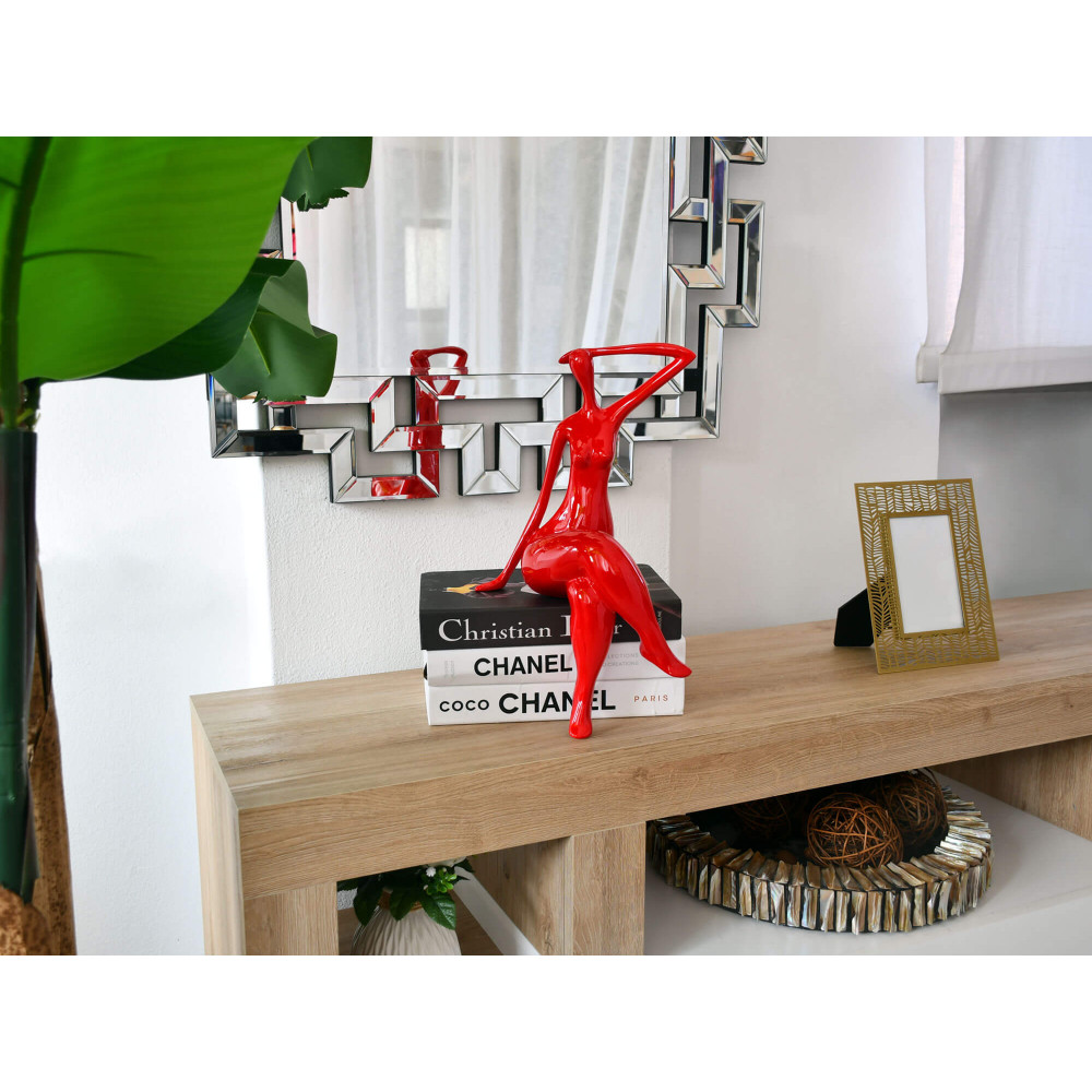 Ambiente living con arredo moderno e scultura di donna in resina rossa con gambe accavallate su bordo di tavolinetto