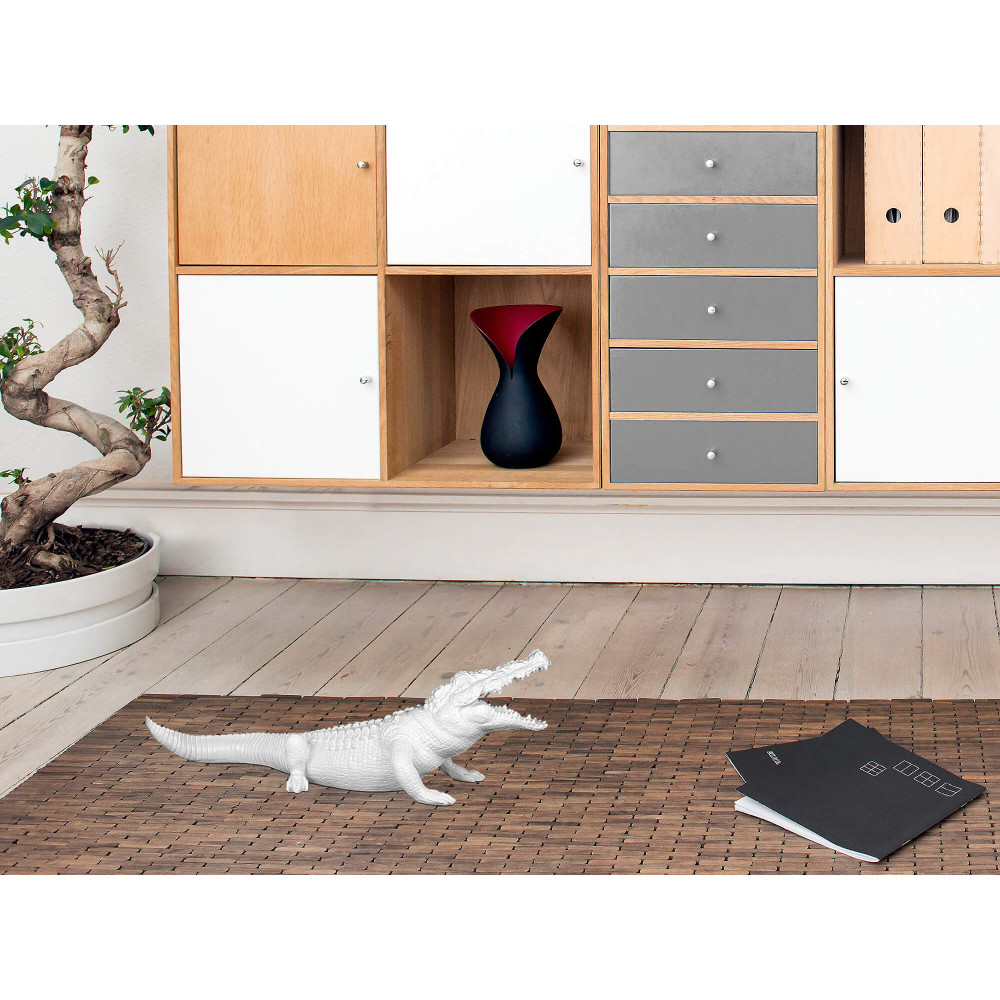 Coccodrillo bianco in resina laccata appoggiato su un tappeto in un soggiorno moderno