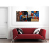 Quadro astratto colorato con decorazioni in rilievo appeso su parete bianca con divano rosso
