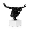 Statua di colore nero che si chiama Equilibrio che rappresenta una figura umana maschile accovacciata su un piedistallo