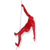 Scultura in resina di colore rosso appesa a una parete e raffigurante uno scalatore