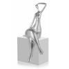 Scultura in resina effetto argento raffigurante donna stilizzata in posizione seduta con gambe accavallate
