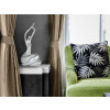 Ambiente living con poltrona, finestra, tende e statuetta argentata di donna con braccia sollevate
