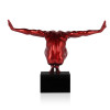 Statua in resina metalizzata rossa di un uomo in equilibrio su un piedistallo visto da dietro