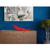 Realistico coccodrillo realizzato in resina rossa appoggiato su un mobile di legno contro una parete azzurra a contrasto
