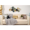 Composizione di foglie di loto stilizzate oro, celesti, argento e nero fissate su divano bianco