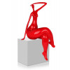 statuetta rossa che raffigura una donna con le gambe accavallate e un braccio dietro la testa