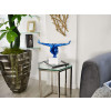 Scultura in resina color azzurro raffigurante uomo in equilibrio su un piedistallo posta su una madia da soggiorno