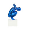 Scultura in resina azzurra con figura di un uomo in equilibrio sul suo piedistallo visto di profilo
