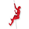 Profilo laterale di scultura rossa laccata di un uomo in arrampicata