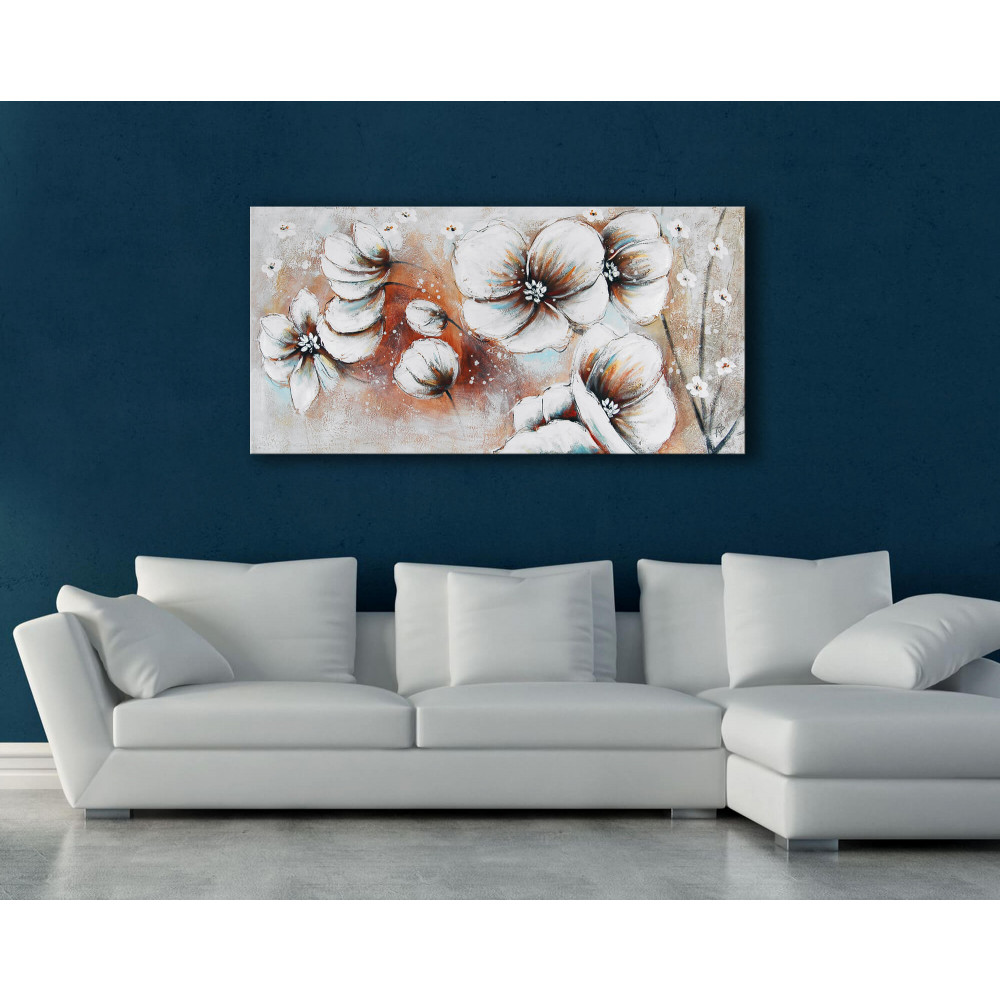 Quadro dipinto a mano raffigurante tre orchidee bianche su uno sfondo grigio posizionato in salotto con divano grigio