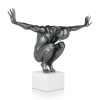 Scultura in resina grigio metallizzato raffigurante un uomo in equilibrio in posizione accovacciata su un piedistallo