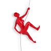 Figura femminile che si arrampica su una parete realizzata in resina rossa laccata