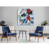 Tela astratta blu, rossa e bianca appesa al muro di un ambiente living con arredo moderno e sedie blu con tavolino di design
