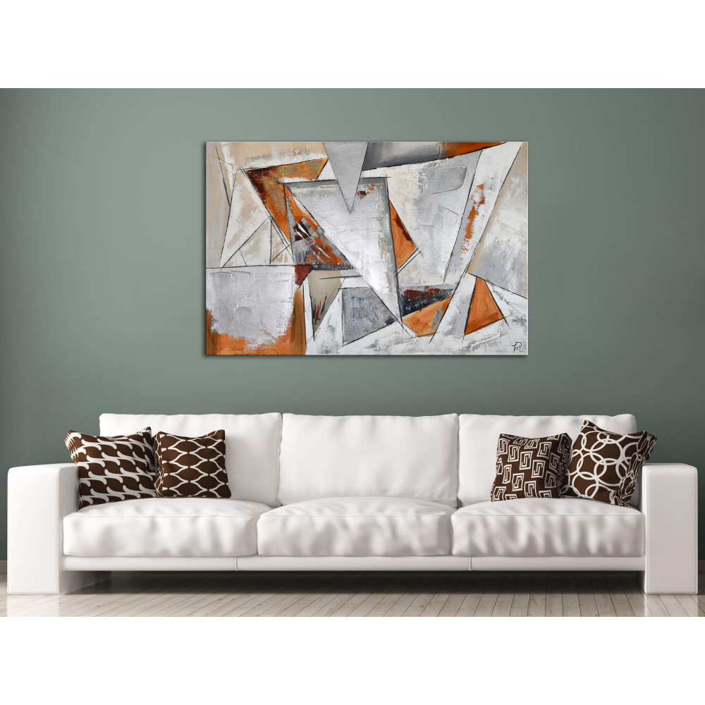 Salotto moderno decorato con dipinto materico astratto con accostamento di triangoli in toni grigio e oro e inserti metallici su parete grigia e nera e presenza di divano bianco