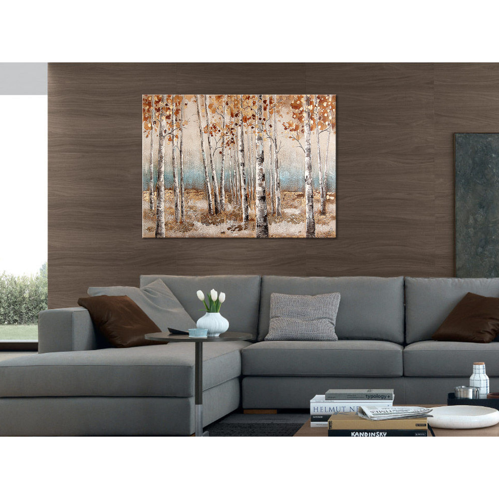 Ambiente living con arredo moderno e quadro raffigurante bosco con foglie oro, marrone e arancioni sullo sfondo