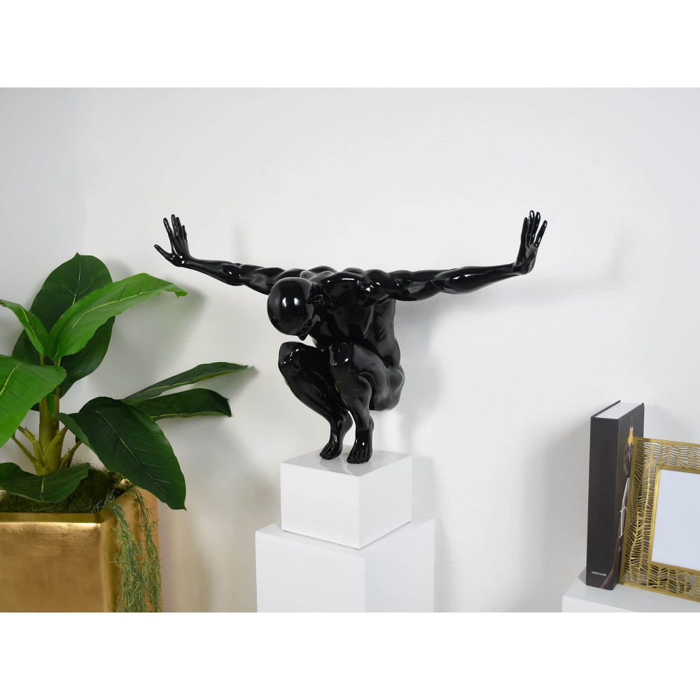 Statua nera di un uomo in equilibrio su un piedistallo in un esempio di arredamento da salotto