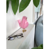 Uccellino rosa in resina accanto a una caffettiera sul ripiano in legno di una cucina