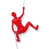 Scultura in resina di colore rosso appesa a parete e raffigurante una donna nell'atto di scalare